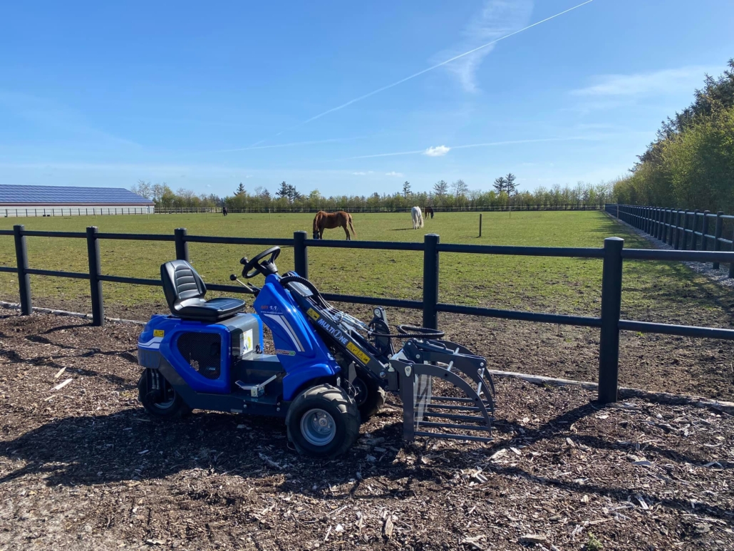 MultiOne mini loader 1 series with silage fork in front of a horse fence