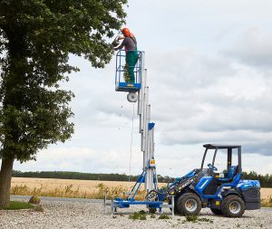 man trimming a tree on an aerial platform