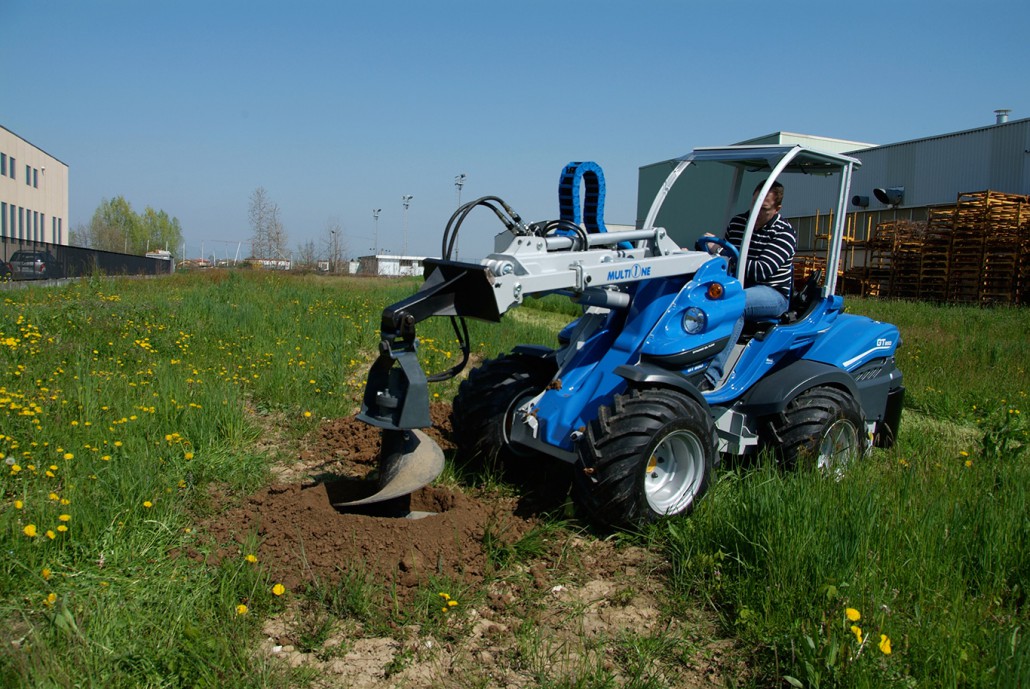 auger for tree with bucket in action in a field