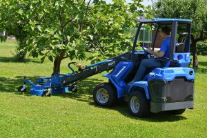 man driving lawn mower in a clean and green garden, near a short tree