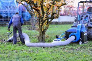 man using a long drain to vacuum leaves