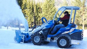 snow blower cleaning a snowy street in a forest during a sunny day
