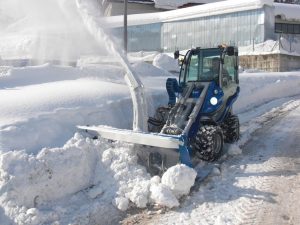 snow blower cleaning a street covered in snow