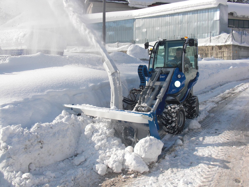 snow blower cleaning a street covered in snow